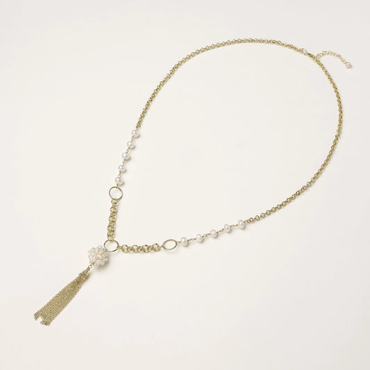 Layered gold-plated necklace with freshwater pearls, central pearl cluster, and chain tassel on cream background.
