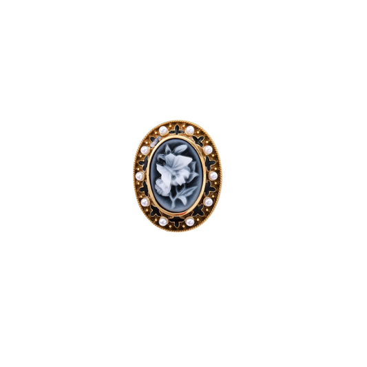 Gold-plated ring with oval blue floral cameo, pearl accents, and black enamel detailing on white background.