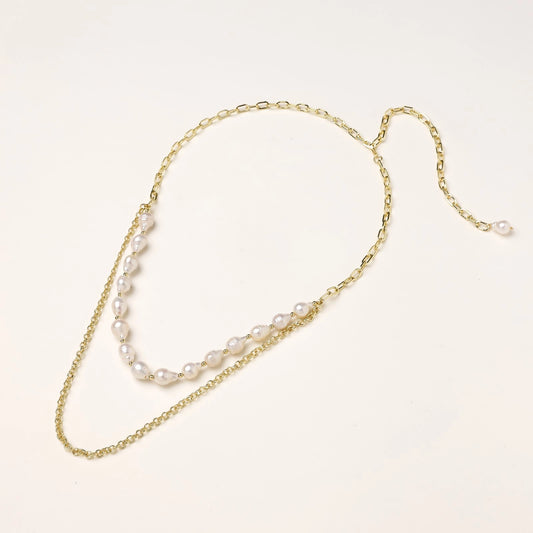 Layered gold chain necklace with irregular freshwater pearls on cream background, showing adjustable dual-strand design.