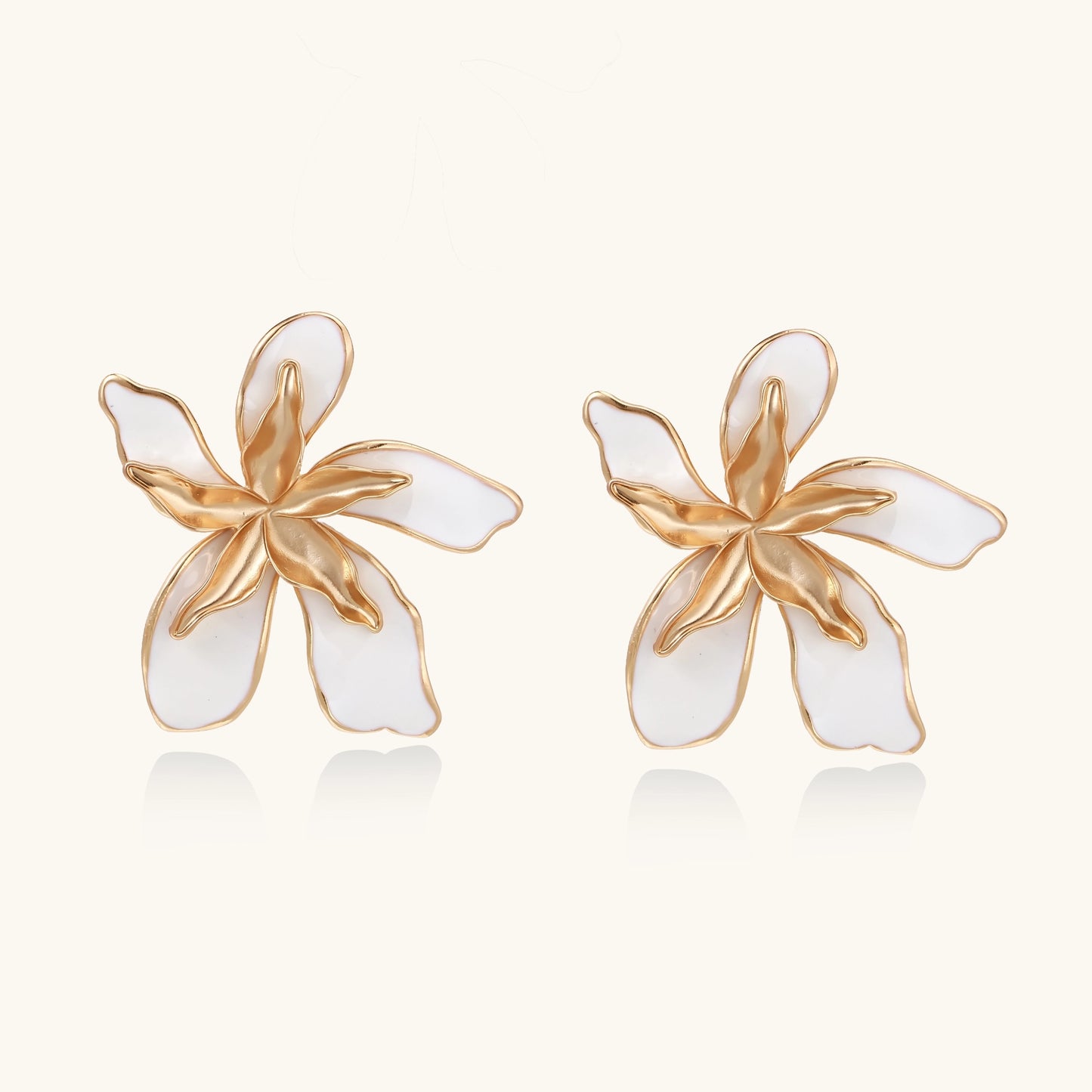Large floral stud earrings with gold-plated brass petals and white enamel centers on neutral background