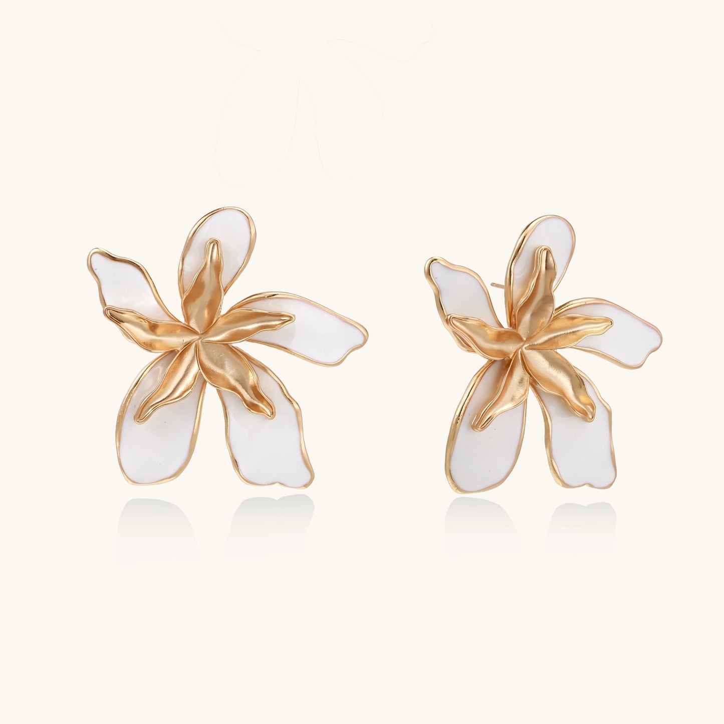Large floral stud earrings with gold-plated brass petals and white enamel centers on neutral background