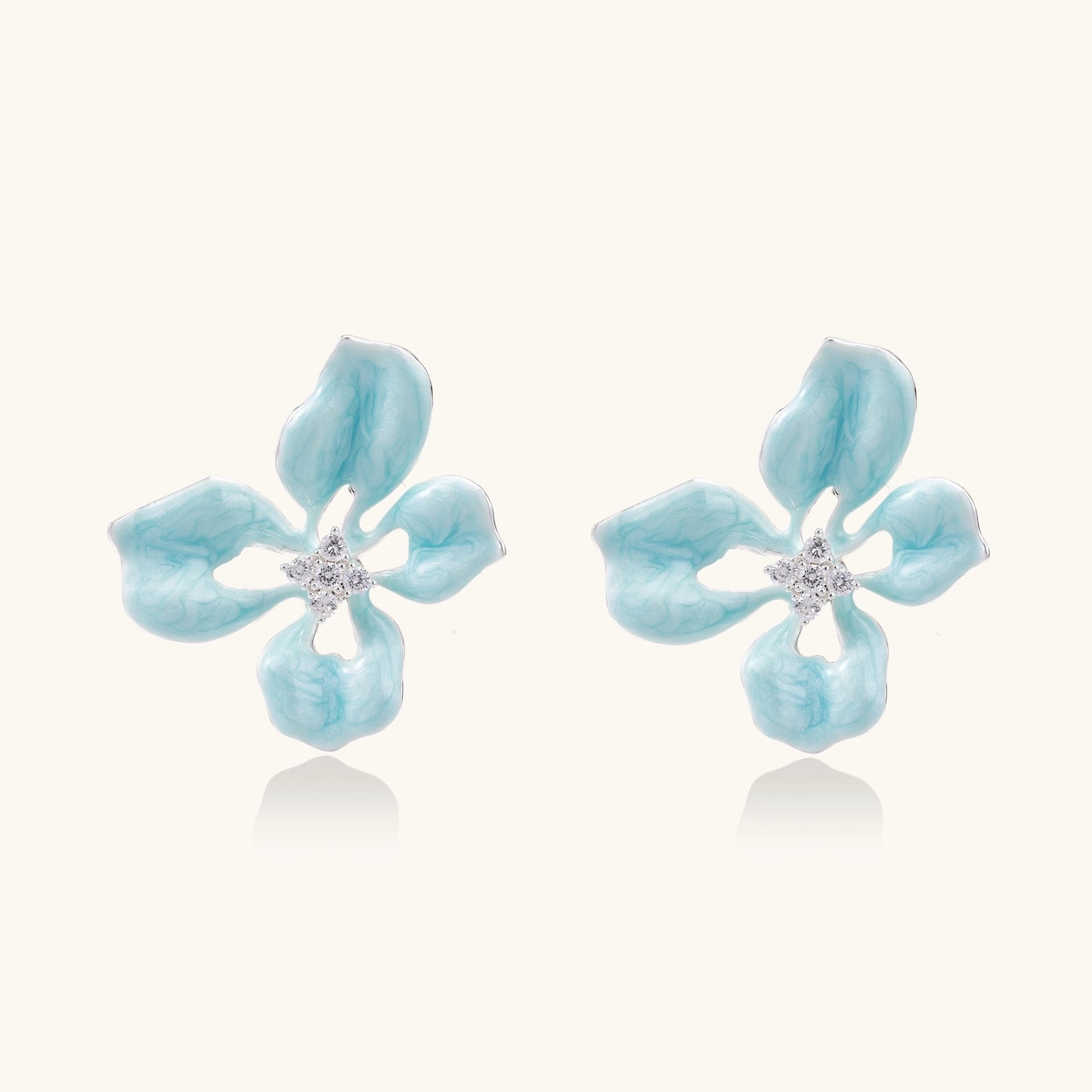Turquoise blue enamel flower earrings with crystal centers and gold-plated brass posts on white background.