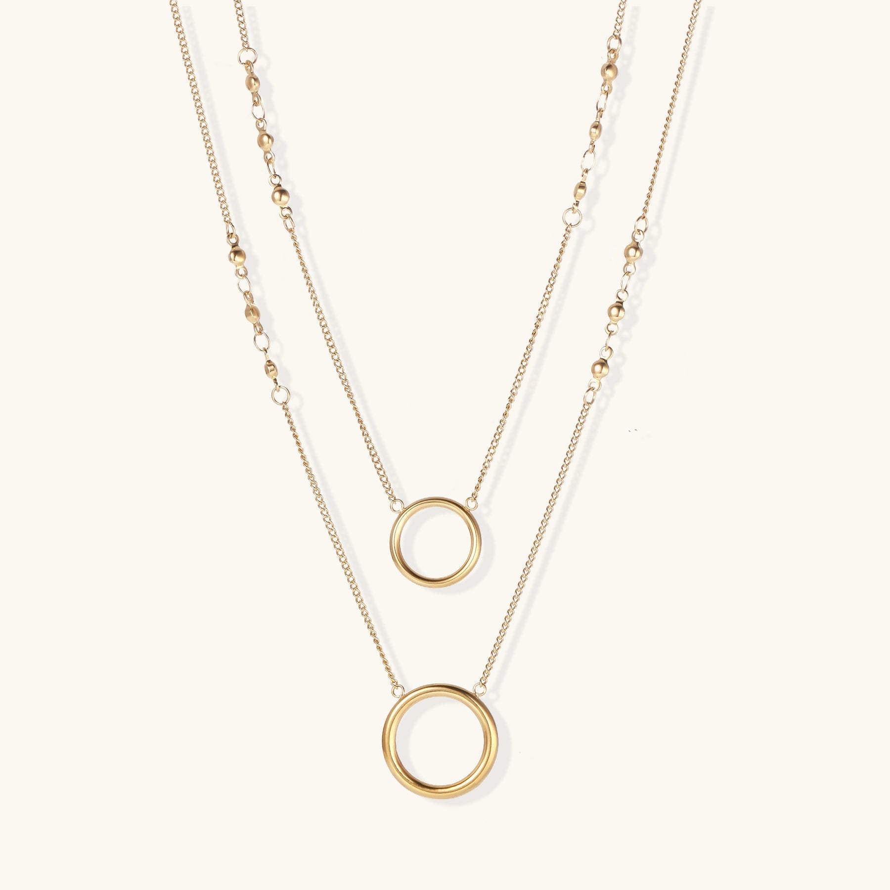 Gold-plated layered necklace set with two circular pendants featuring white centers on delicate chains.