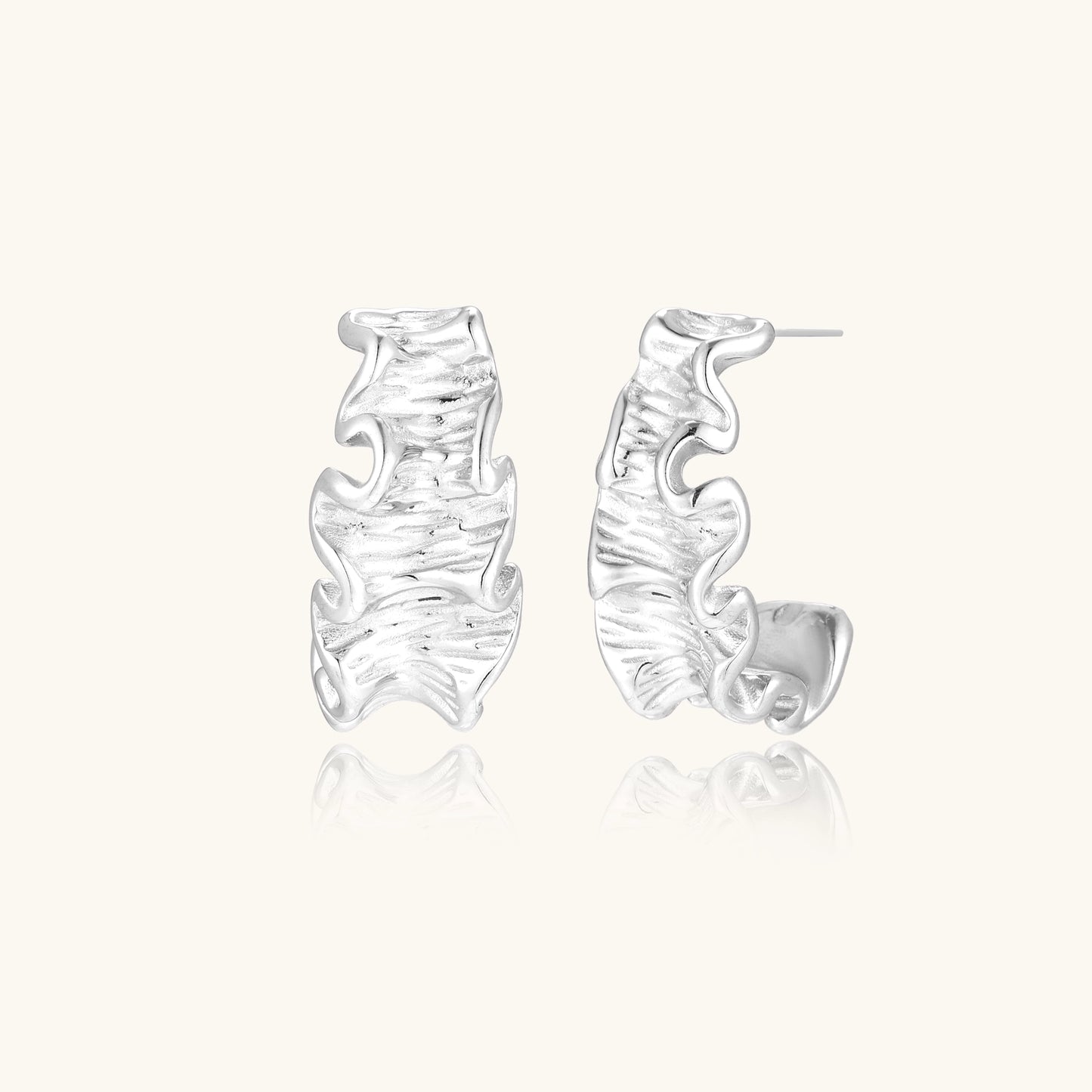 Textured gold-plated hoop earrings with flowing ripple design displayed on clean white background.