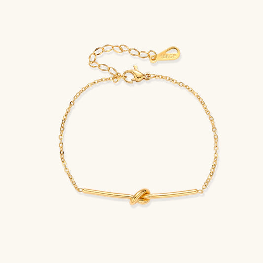 Delicate gold-plated chain bracelet with twisted knot bar detail and adjustable extender chain on white background.
