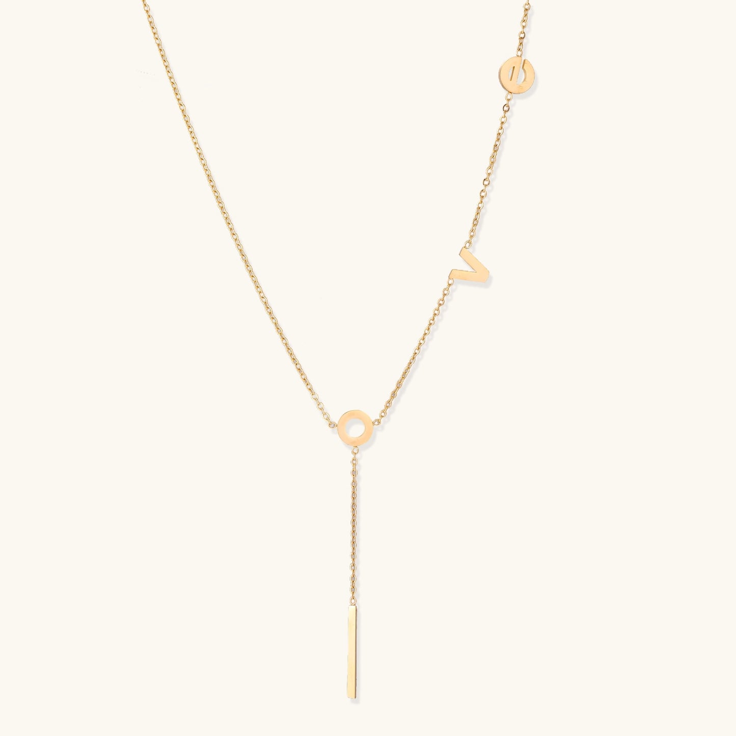 Gold-plated lariat necklace spelling LOVE with letter charms and vertical bar pendant on white background.