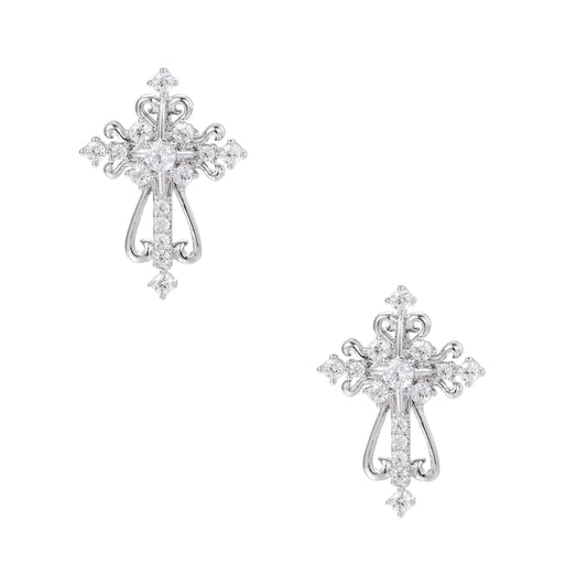 White gold-plated baroque cross studs with zirconia stones and ornate scrollwork on cream background.