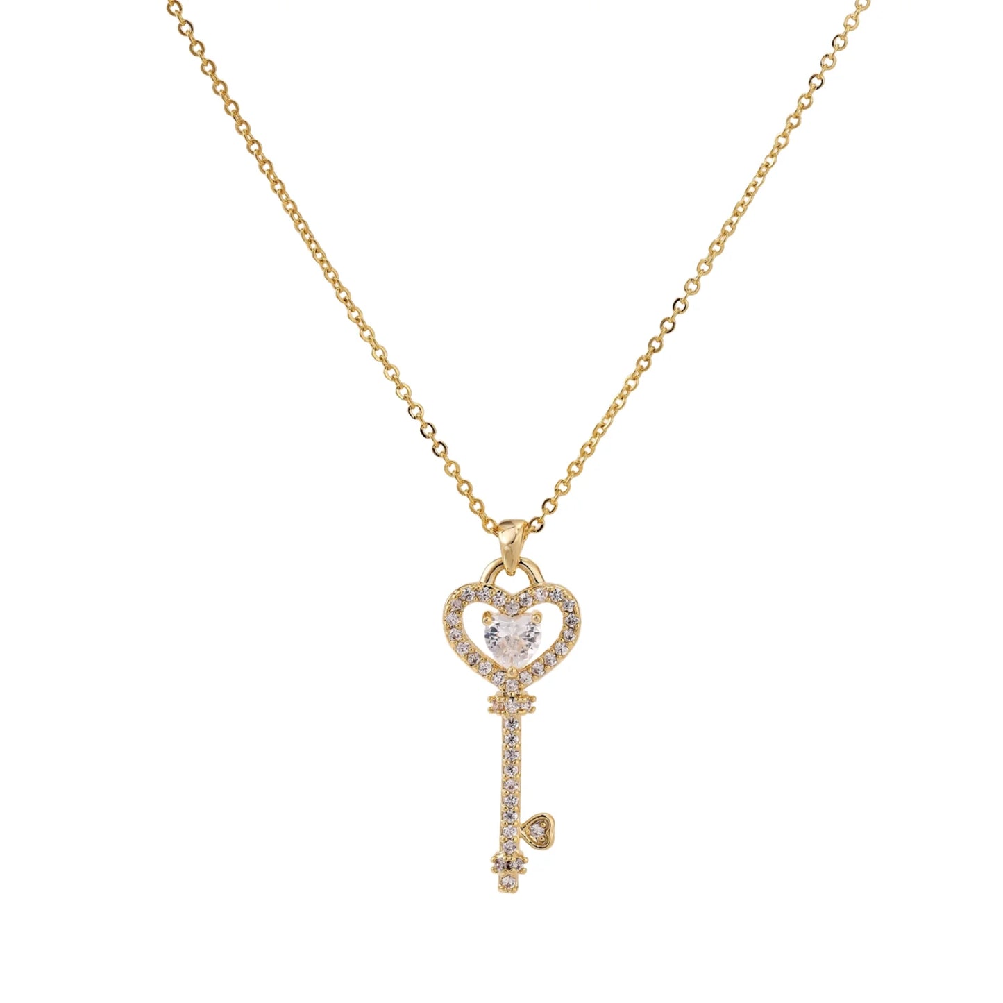 Delicate gold key pendant with heart-shaped bow and crystal pavé detailing on fine chain against cream background.
